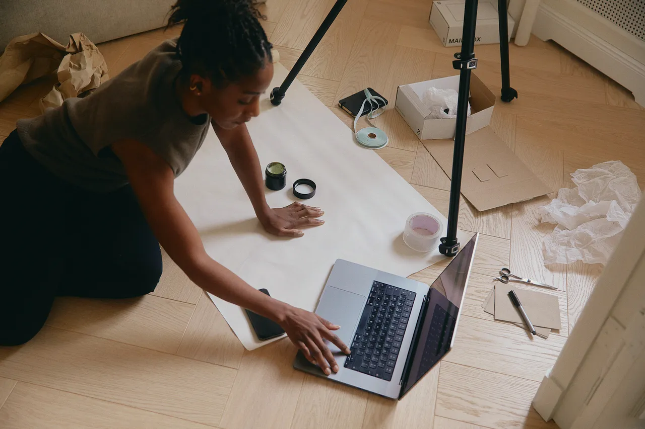 A woman working on her laptop on the floor of her studio